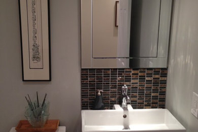 Foto di un piccolo bagno di servizio contemporaneo con lavabo integrato, ante lisce, ante in legno bruno, WC a due pezzi, piastrelle marroni, piastrelle a mosaico e pareti grigie