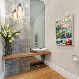 Contemporary powder room in Melbourne with gray tile, beige walls, medium hardwood floors, a vessel sink, wood benchtops, brown floor and brown benchtops.