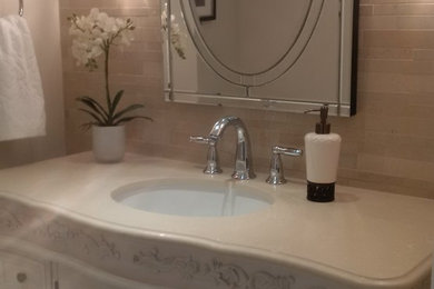 Example of a mid-sized tuscan beige tile and porcelain tile porcelain tile powder room design in Toronto with furniture-like cabinets, white cabinets, a one-piece toilet, beige walls, an undermount sink and quartzite countertops