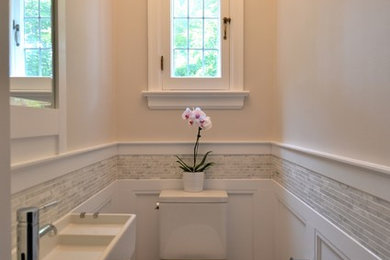 Imagen de aseo tradicional pequeño con lavabo suspendido, baldosas y/o azulejos grises, azulejos en listel, sanitario de dos piezas, paredes beige y suelo de madera en tonos medios