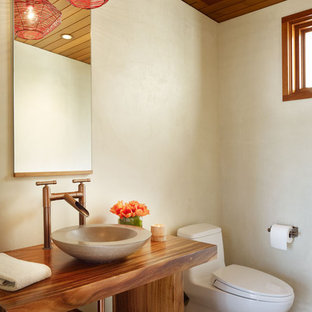 Idées déco pour un WC et toilettes exotique de taille moyenne avec une vasque, un placard sans porte, des portes de placard en bois sombre, un mur beige, un sol en carrelage de porcelaine, un plan de toilette en bois, un sol marron et un plan de toilette marron.