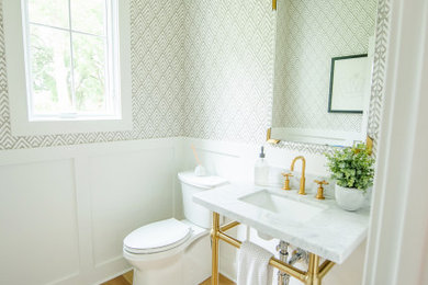 Powder room - contemporary light wood floor and wallpaper powder room idea in Cincinnati with a two-piece toilet, white walls, a wall-mount sink, marble countertops, white countertops and a freestanding vanity