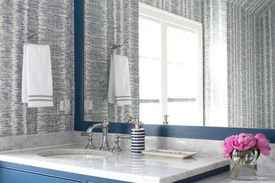 Foto di un bagno di servizio classico con ante a filo, ante blu, pareti multicolore, lavabo sottopiano e top bianco