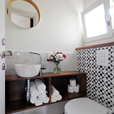 Powder room - contemporary black and white tile powder room idea in Other with a wall-mount toilet, white walls and a vessel sink