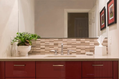 Example of a small trendy stone tile and beige tile porcelain tile and beige floor powder room design in New York with an undermount sink, red cabinets, solid surface countertops, gray walls, flat-panel cabinets and gray countertops