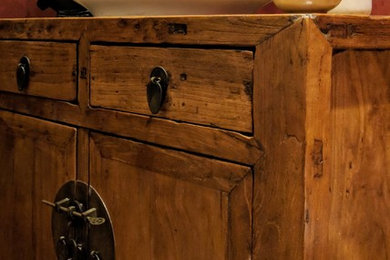 Diseño de aseo tradicional renovado pequeño con armarios tipo mueble, puertas de armario de madera oscura, paredes rojas, suelo de baldosas de porcelana, lavabo sobreencimera, encimera de madera y suelo negro