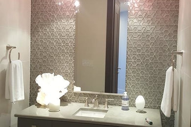 Inredning av ett modernt mellanstort toalett, med släta luckor, grå skåp, grå kakel, mosaik, vita väggar, klinkergolv i porslin, ett avlångt handfat, granitbänkskiva och beiget golv