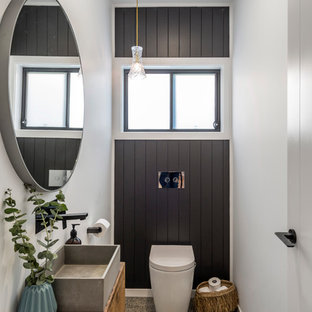 Inspiration for a beach style powder room in Gold Coast - Tweed with flat-panel cabinets, medium wood cabinets, a one-piece toilet, white walls, concrete floors, a vessel sink, wood benchtops and brown benchtops.
