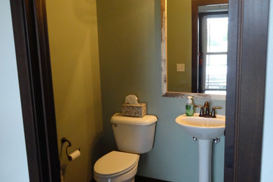 Mid-sized arts and crafts vinyl floor and brown floor powder room photo in Milwaukee with a two-piece toilet, green walls and a pedestal sink