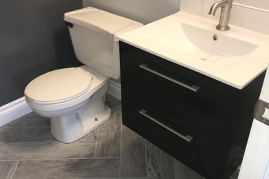 Inredning av ett modernt litet vit vitt toalett, med svarta skåp, en toalettstol med separat cisternkåpa, grå väggar, klinkergolv i keramik, ett väggmonterat handfat, granitbänkskiva och grått golv
