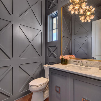 Example of a large transitional medium tone wood floor powder room design in Austin with gray cabinets, a two-piece toilet, gray walls, an undermount sink, marble countertops and furniture-like cabinets