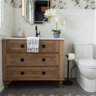 Cette image montre un WC et toilettes craftsman de taille moyenne avec un placard en trompe-l'oeil, des portes de placard en bois brun, un sol en carrelage de porcelaine, un lavabo encastré, un plan de toilette en quartz modifié, un sol gris et un plan de toilette blanc.