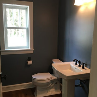 Exemple d'un WC et toilettes craftsman de taille moyenne avec un WC séparé, un mur bleu, un sol en bois foncé et un lavabo de ferme.