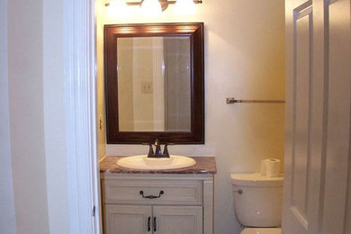 Bild på ett mellanstort vintage toalett, med beige skåp, beige väggar, klinkergolv i keramik, granitbänkskiva, luckor med infälld panel, en toalettstol med separat cisternkåpa, ett nedsänkt handfat och beiget golv