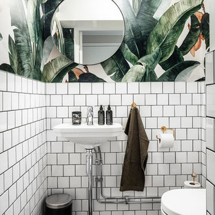 Inredning av ett minimalistiskt litet svart svart toalett, med öppna hyllor, vita skåp, en vägghängd toalettstol, vit kakel, keramikplattor, vita väggar, klinkergolv i keramik, svart golv och ett piedestal handfat