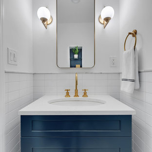 Idée de décoration pour un WC et toilettes tradition avec un placard à porte shaker, des portes de placard bleues, un carrelage blanc, un mur blanc, un lavabo encastré et un plan de toilette blanc.