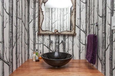 Aménagement d'un WC et toilettes contemporain avec une vasque, un plan de toilette en bois, un mur multicolore, un sol en bois brun et un plan de toilette marron.