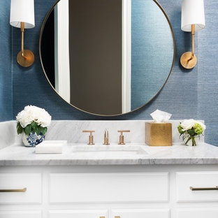 Idée de décoration pour un WC et toilettes tradition avec un placard avec porte à panneau surélevé, des portes de placard blanches, un mur bleu, un lavabo encastré, un plan de toilette en marbre et un plan de toilette gris.