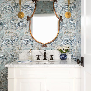 Immagine di un piccolo bagno di servizio chic con ante bianche, WC monopezzo, pareti multicolore, parquet scuro, lavabo sottopiano, top in marmo, pavimento marrone, ante con riquadro incassato e top bianco