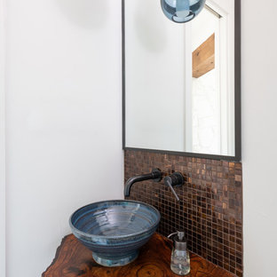 Cette photo montre un WC et toilettes sud-ouest américain de taille moyenne avec un carrelage marron, carrelage en mosaïque, un mur blanc, une vasque, un plan de toilette en bois et un plan de toilette marron.