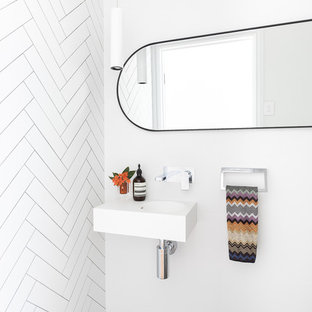 Design ideas for a mid-sized contemporary powder room in Brisbane with a one-piece toilet, white tile, ceramic tile, white walls, cement tiles, a wall-mount sink, engineered quartz benchtops, grey floor and white benchtops.