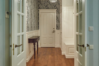 Ejemplo de entrada tradicional con suelo de madera en tonos medios, puerta doble y puerta blanca