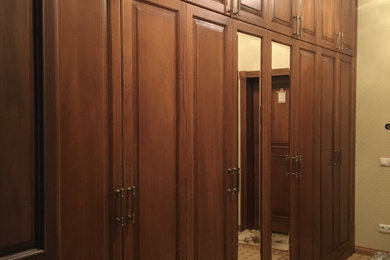 Modelo de hall clásico grande con paredes beige, suelo de baldosas de cerámica, puerta simple, puerta de madera oscura, suelo beige y papel pintado