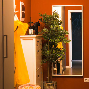 Inspiration pour une petit porte d'entrée nordique avec un mur orange, sol en stratifié, une porte simple, une porte blanche et un sol marron.