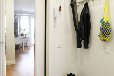 Imagen de entrada actual pequeña con paredes blancas, suelo de madera en tonos medios, puerta simple y puerta blanca