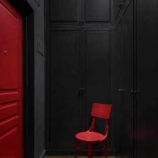Idée de décoration pour une entrée urbaine de taille moyenne avec un couloir, un mur noir, sol en stratifié, une porte simple, une porte rouge et un sol marron.