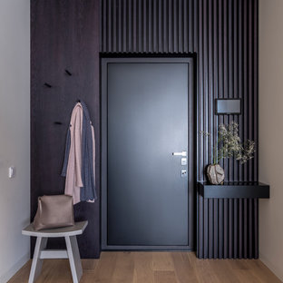 Aménagement d'une porte d'entrée contemporaine avec un mur noir, un sol en bois brun, une porte simple, une porte noire et un sol marron.
