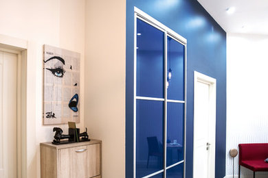 Foto de entrada contemporánea pequeña con paredes azules, suelo de baldosas de porcelana, puerta simple y puerta de madera clara