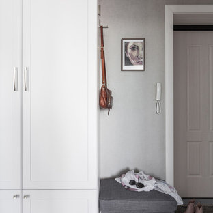 Réalisation d'une petit porte d'entrée tradition avec un mur gris, sol en stratifié, une porte simple, une porte en bois clair et un sol beige.