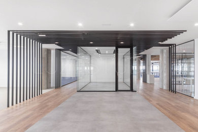 Immagine di un ingresso o corridoio industriale con pareti bianche, pavimento in legno massello medio e pavimento marrone