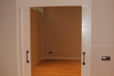 Ejemplo de recibidores y pasillos tradicionales renovados de tamaño medio con paredes blancas y suelo de madera en tonos medios