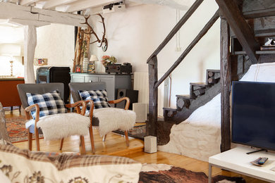 Imagen de sala de estar con rincón musical abierta rural de tamaño medio con paredes blancas, suelo de madera clara, televisor independiente y suelo marrón