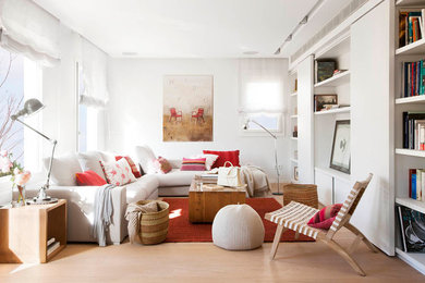 Imagen de sala de estar con biblioteca abierta escandinava de tamaño medio sin chimenea con paredes blancas y suelo de madera en tonos medios
