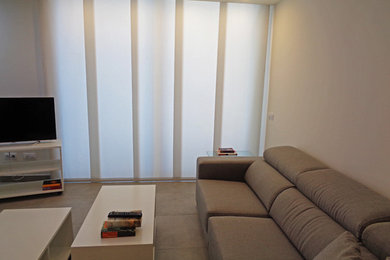 Imagen de sala de estar cerrada actual de tamaño medio sin chimenea con paredes beige, suelo de baldosas de cerámica y televisor independiente