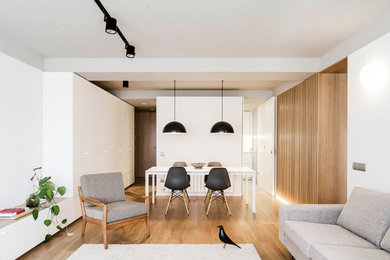Foto de sala de estar abierta escandinava de tamaño medio sin chimenea con paredes blancas y suelo de madera clara