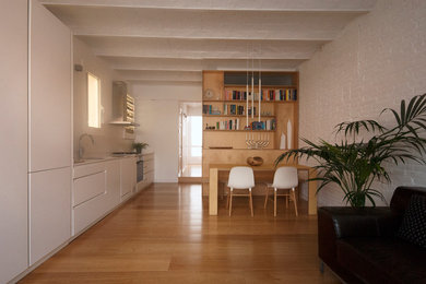 Diseño de sala de estar abierta y abovedada nórdica de tamaño medio sin televisor con paredes blancas, suelo de madera en tonos medios y ladrillo