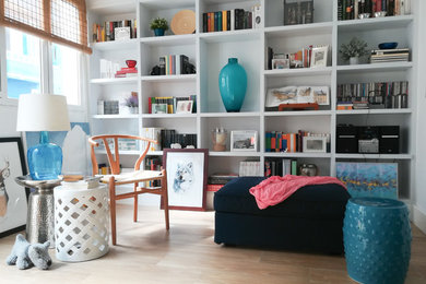 Modelo de sala de estar con biblioteca abierta clásica renovada de tamaño medio sin chimenea y televisor con paredes blancas, suelo de baldosas de porcelana y suelo marrón