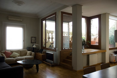 Ejemplo de sala de estar abierta actual de tamaño medio sin chimenea y televisor con paredes beige y suelo de madera en tonos medios