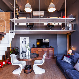 Imagen de sala de estar abierta, contemporánea, con paredes azules, suelo de madera en tonos medios, televisor independiente y suelo marrón