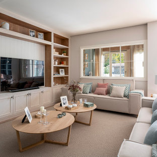 Modelo de sala de estar abierta, escandinava, grande, sin chimenea, con paredes beige, suelo laminado, televisor independiente y suelo beige