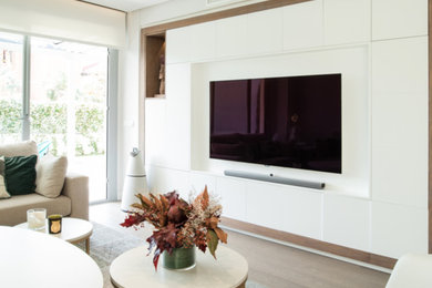 Imagen de sala de estar abierta moderna grande con paredes blancas, suelo de madera en tonos medios, televisor colgado en la pared y suelo beige