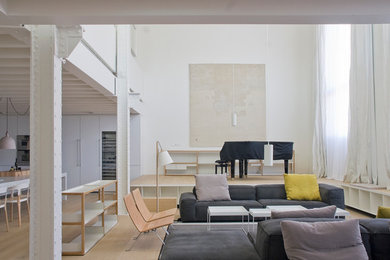 Modelo de sala de estar abierta escandinava grande sin chimenea y televisor con paredes blancas y suelo de madera clara