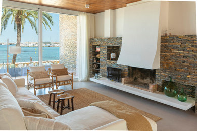 Ejemplo de sala de estar abierta mediterránea extra grande con paredes blancas, suelo de cemento, todas las chimeneas, marco de chimenea de piedra y suelo gris