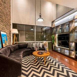 Imagen de sala de estar industrial con paredes multicolor, suelo de madera en tonos medios y televisor colgado en la pared