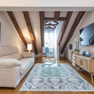 Foto de sala de estar mediterránea con paredes blancas, suelo de madera en tonos medios, televisor colgado en la pared y suelo marrón