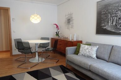 Modelo de sala de estar vintage de tamaño medio con paredes blancas y suelo de madera en tonos medios
